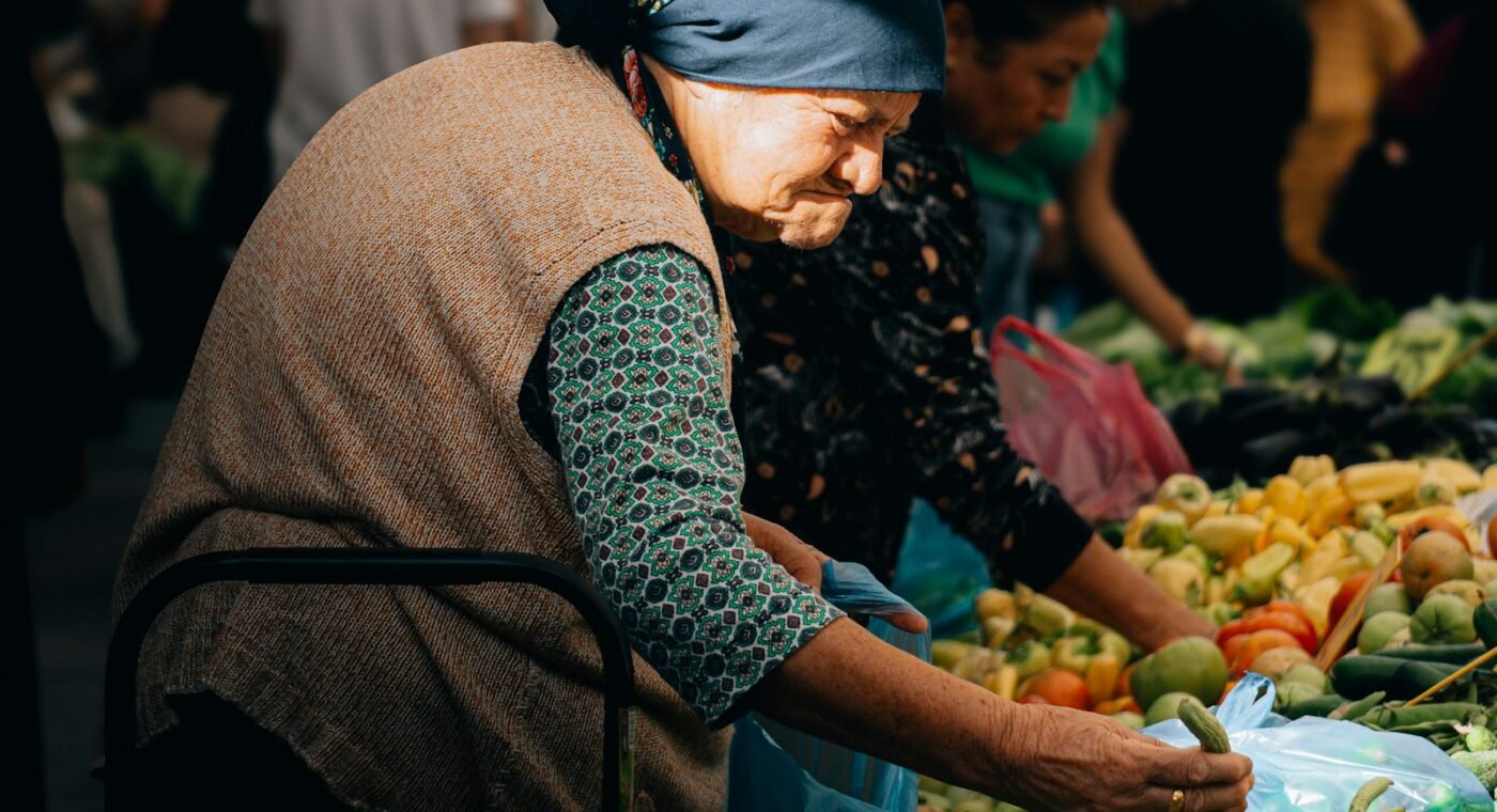 Mulher idosa escolhe legumes frescos num mercado
