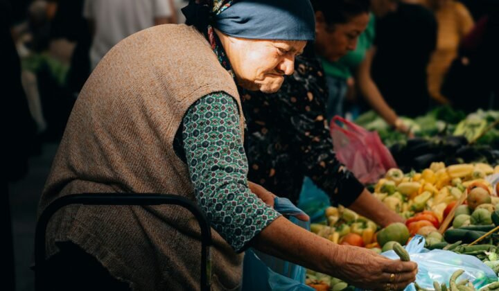 Mulher idosa escolhe legumes frescos num mercado