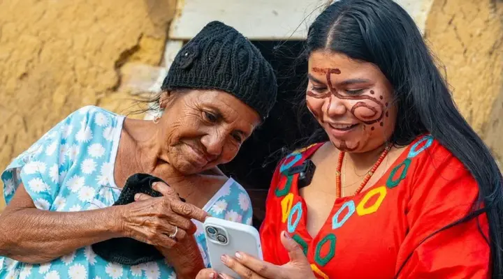 Mulher idosa e jovem colombiana a consultar um telemóvel