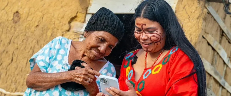 Mulher idosa e jovem colombiana a consultar um telemóvel