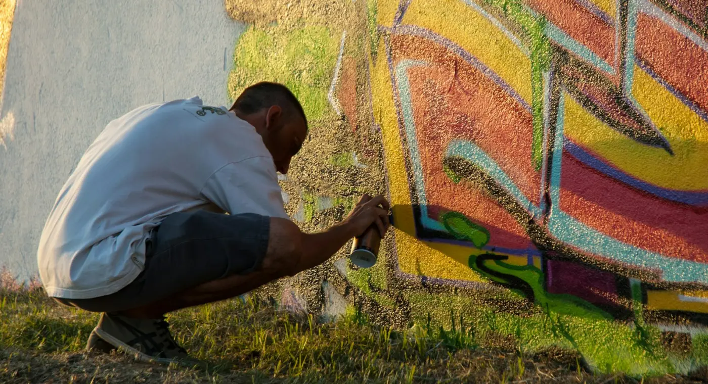 Jovem a pintar um mural colorido numa parede