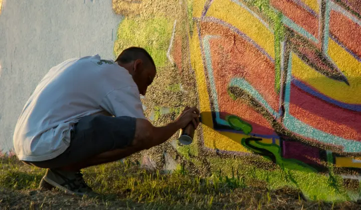 Jovem a pintar um mural colorido numa parede