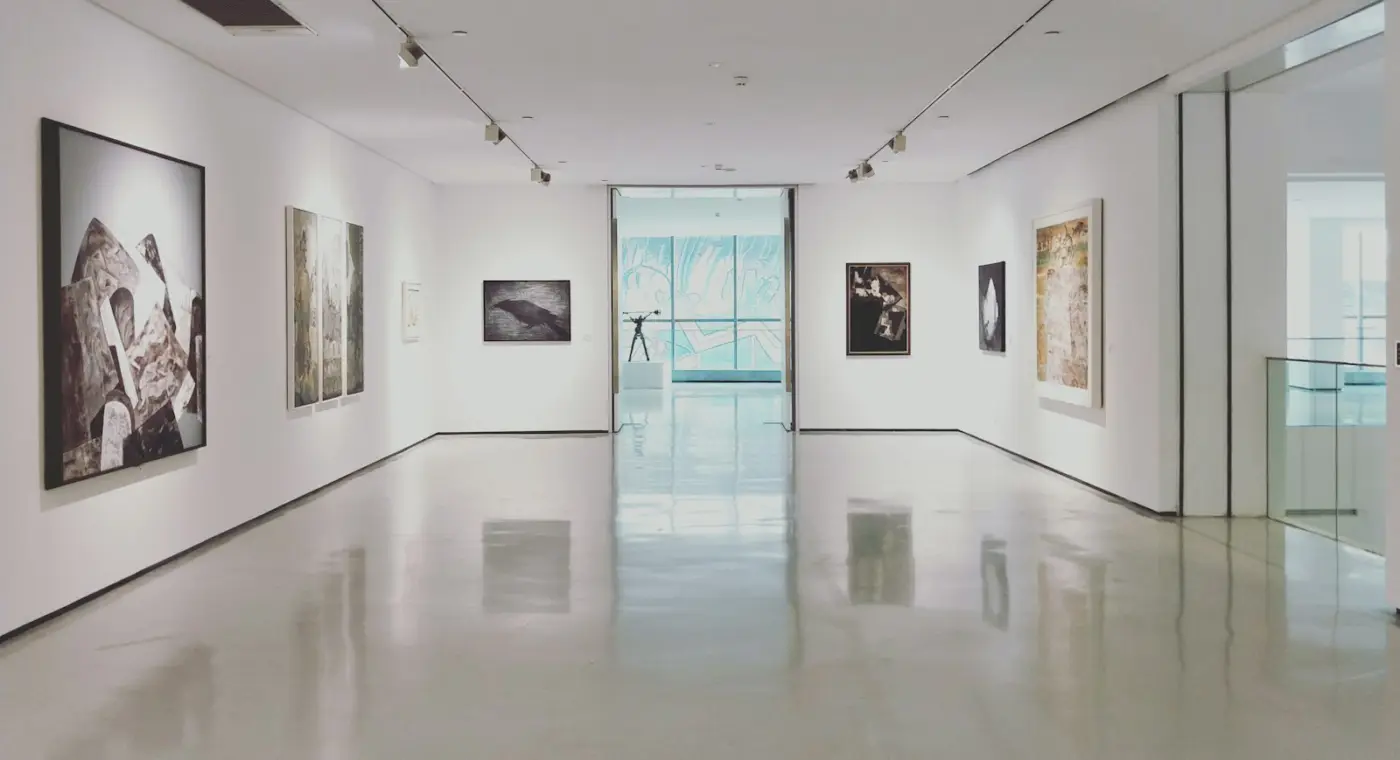 Sala de museu branca e luminosa com quadros nas paredes